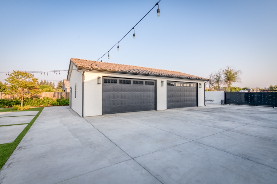 26x44 3-car garage with lighting over top and two brown overhead doors with transom windows