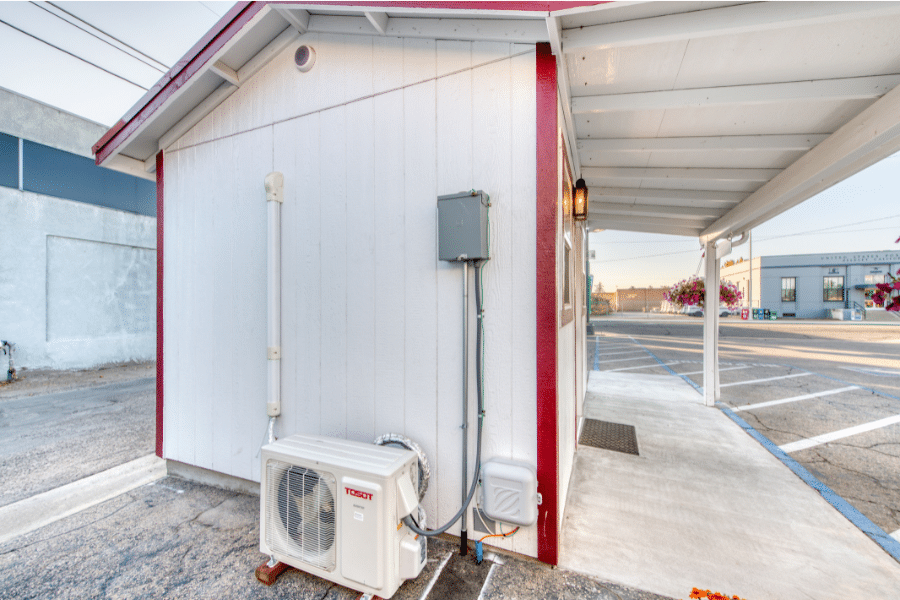 Mini split AC_heating unit on the side of a tan and red trimmed 10x12 custom office shed