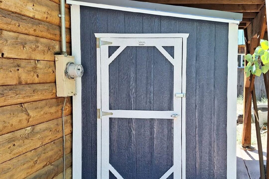 blue and white trimmed lean to shed against side of window house and underneath side deck