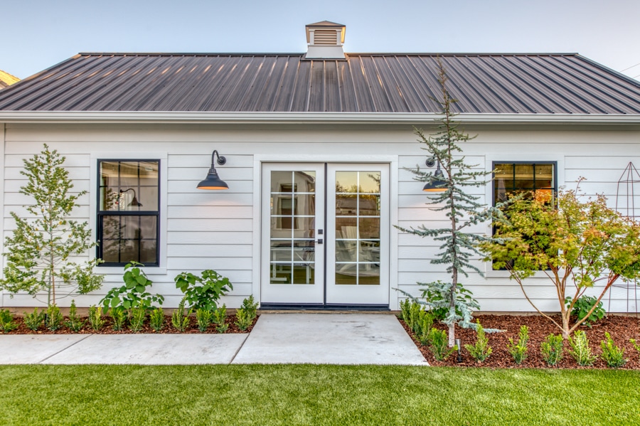 close up of white 16x30 pool house and game room with French double doors and garden