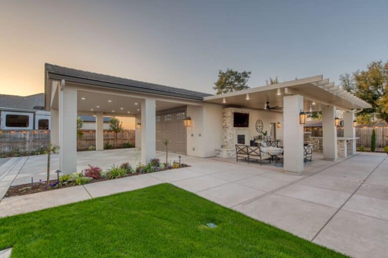 two custom buildings for sale near Goshen CA featuring one side with a tan and brown two car garage with overhang featuring black metal roof and other connected side a pavilion with TV fireplace and seating area