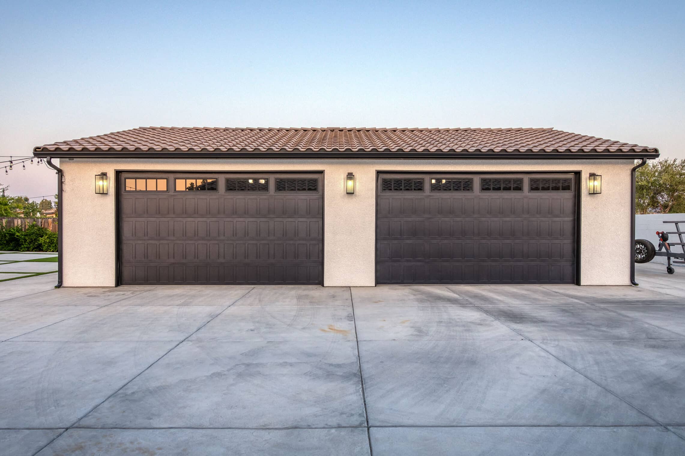 custom four garage with tan siding and two brown overhead doors