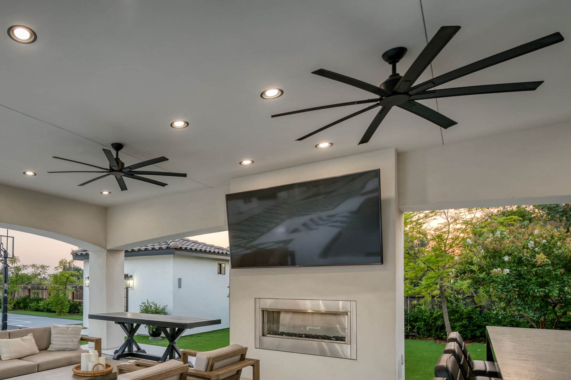 custom pavilion with fans and lights on ceiling a TV and fireplace on one wall and bar set up as well as seating area