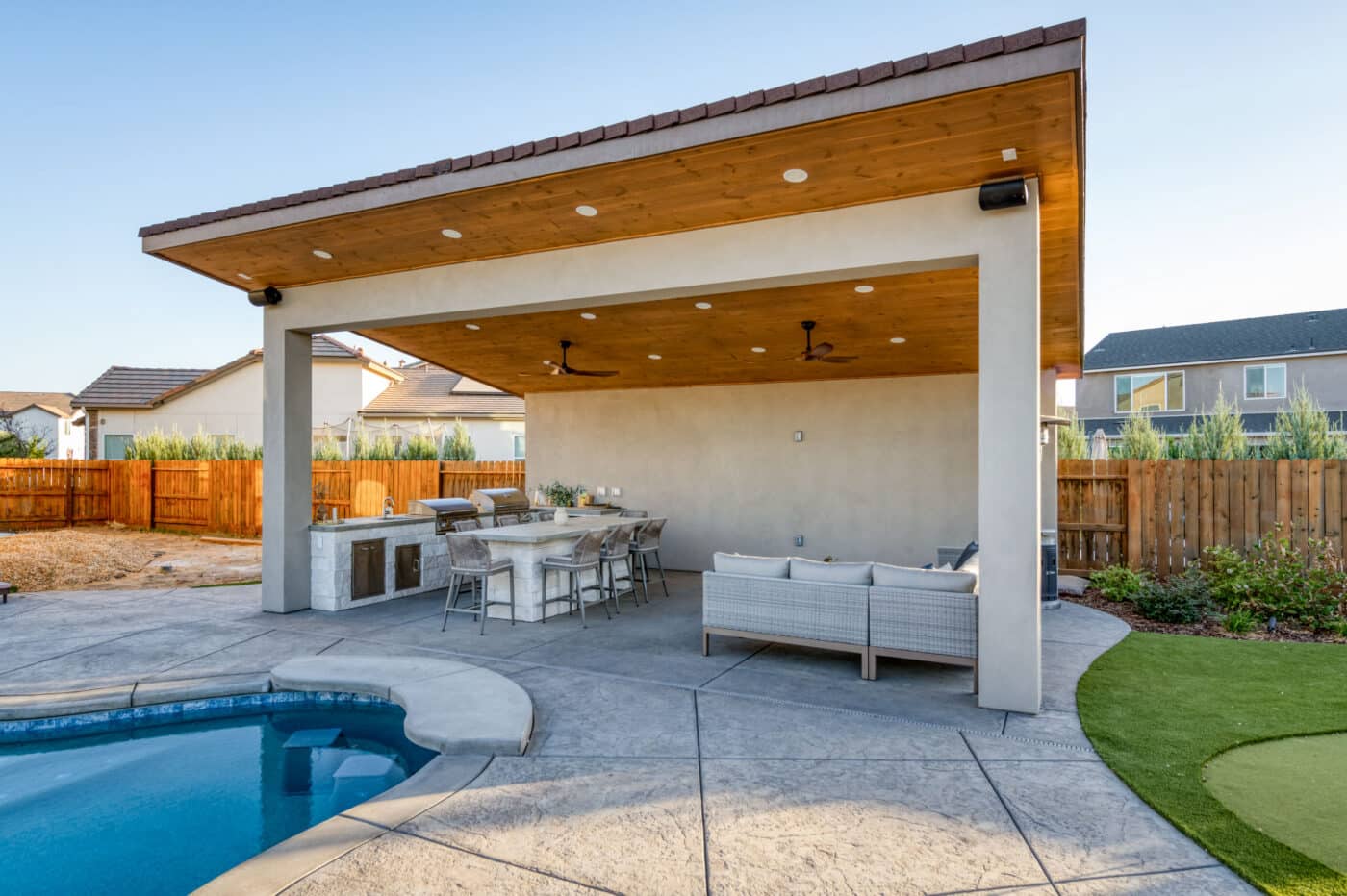 custom pavilion with sloped roof over seating area and outdoor kitchen