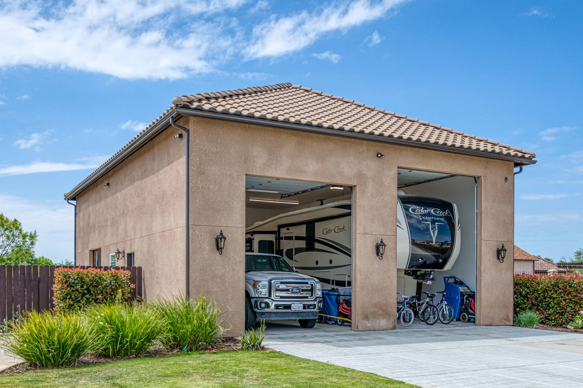 tan custom garages in Clovis CA with open doors with truck and camper inside