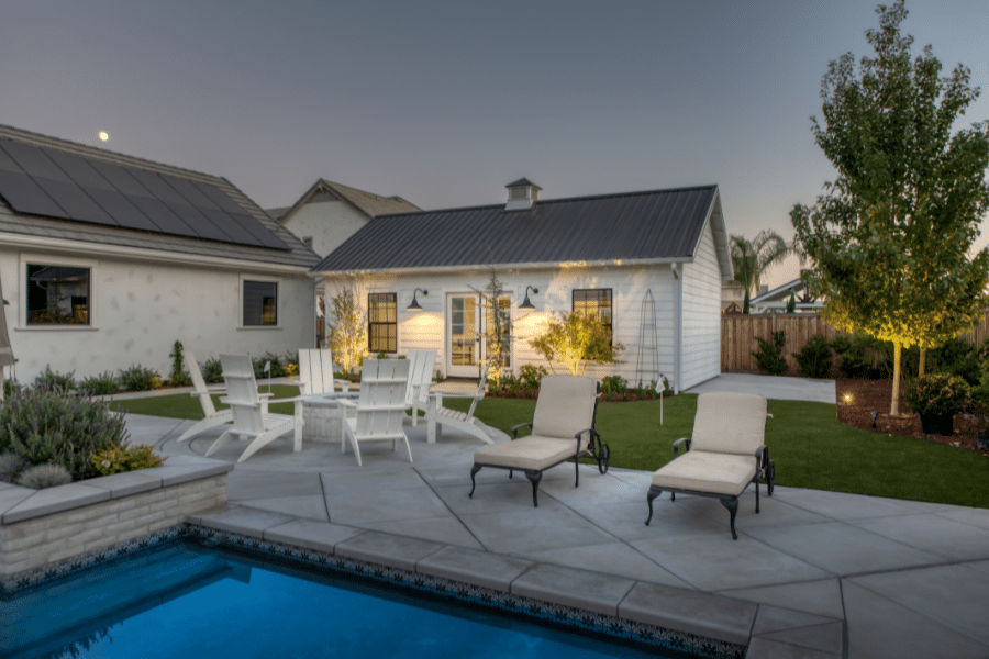 custom white cabana with black metal roof by fire pit and pool