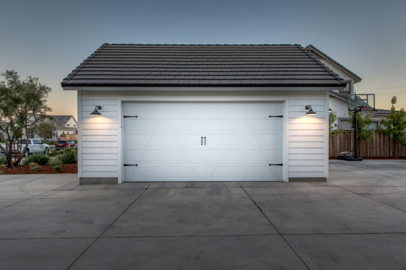 custom white one car garage with two lights lit up at night on either side of the overhead door