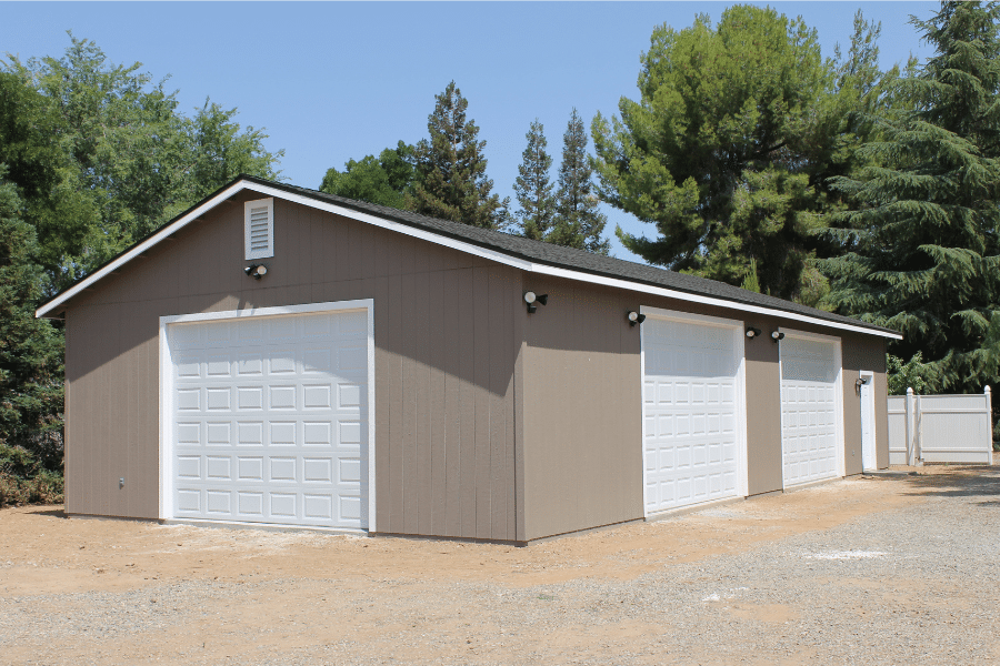 dark tan three car garage with shingle roof and three white overhead doors