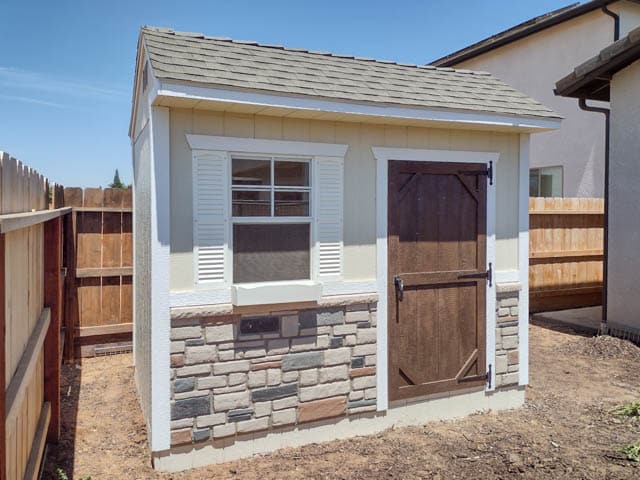 white elite garden sheds in Clovis CA with stone detailing and brown door