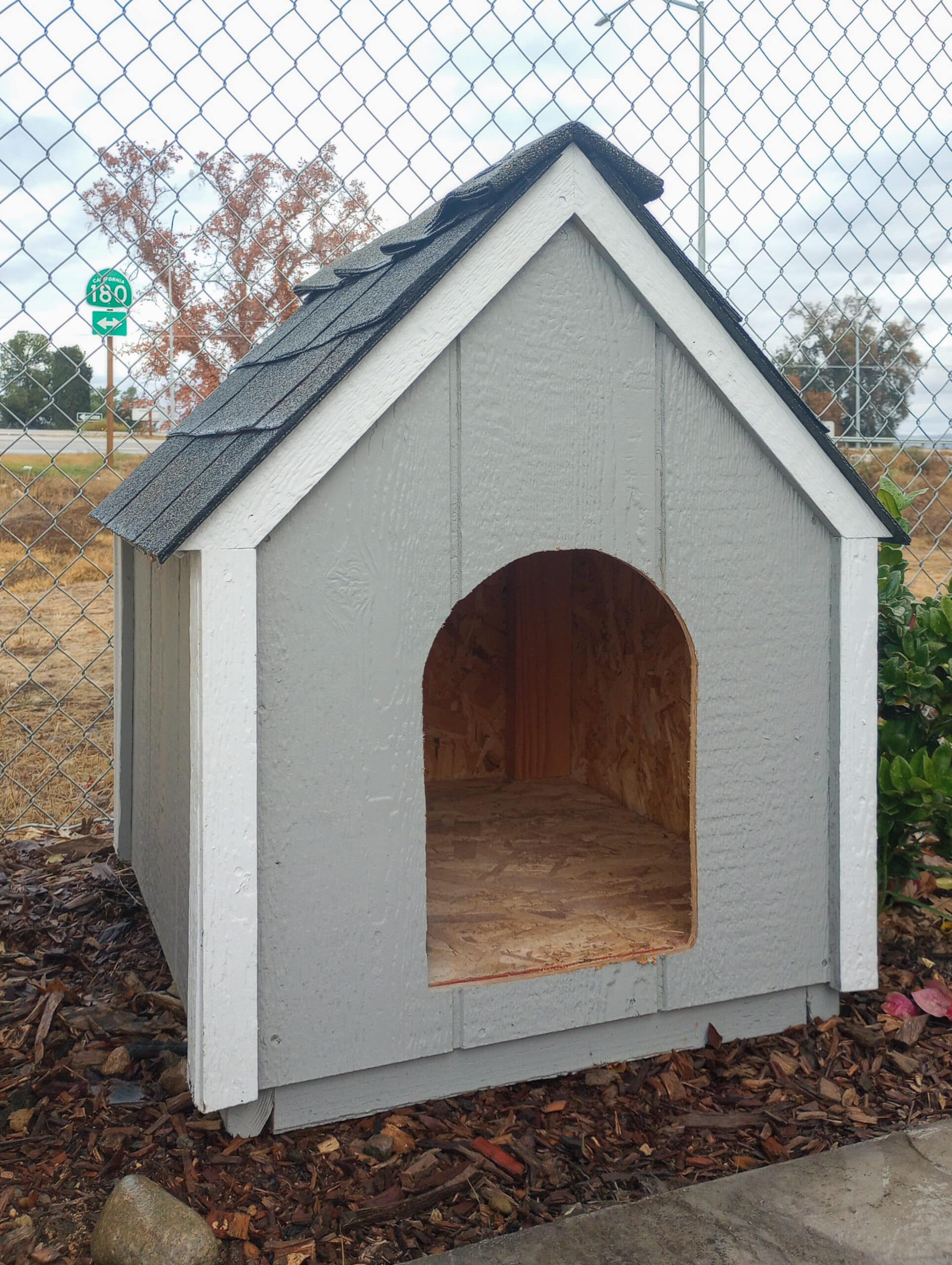 gray dog house with white trim and shingle roof