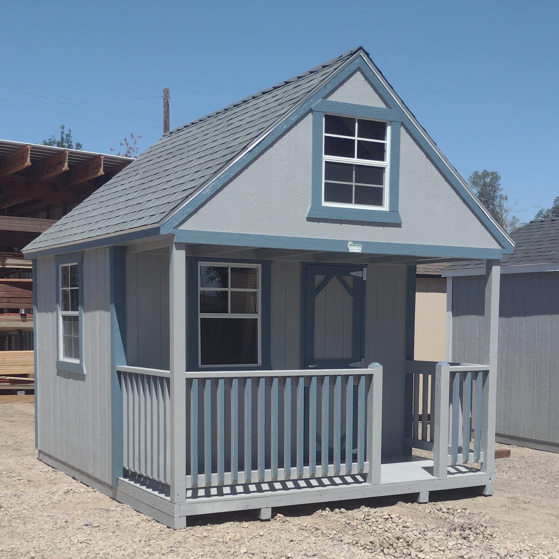 gray playhouse with blue trim shingle roof and a front porch