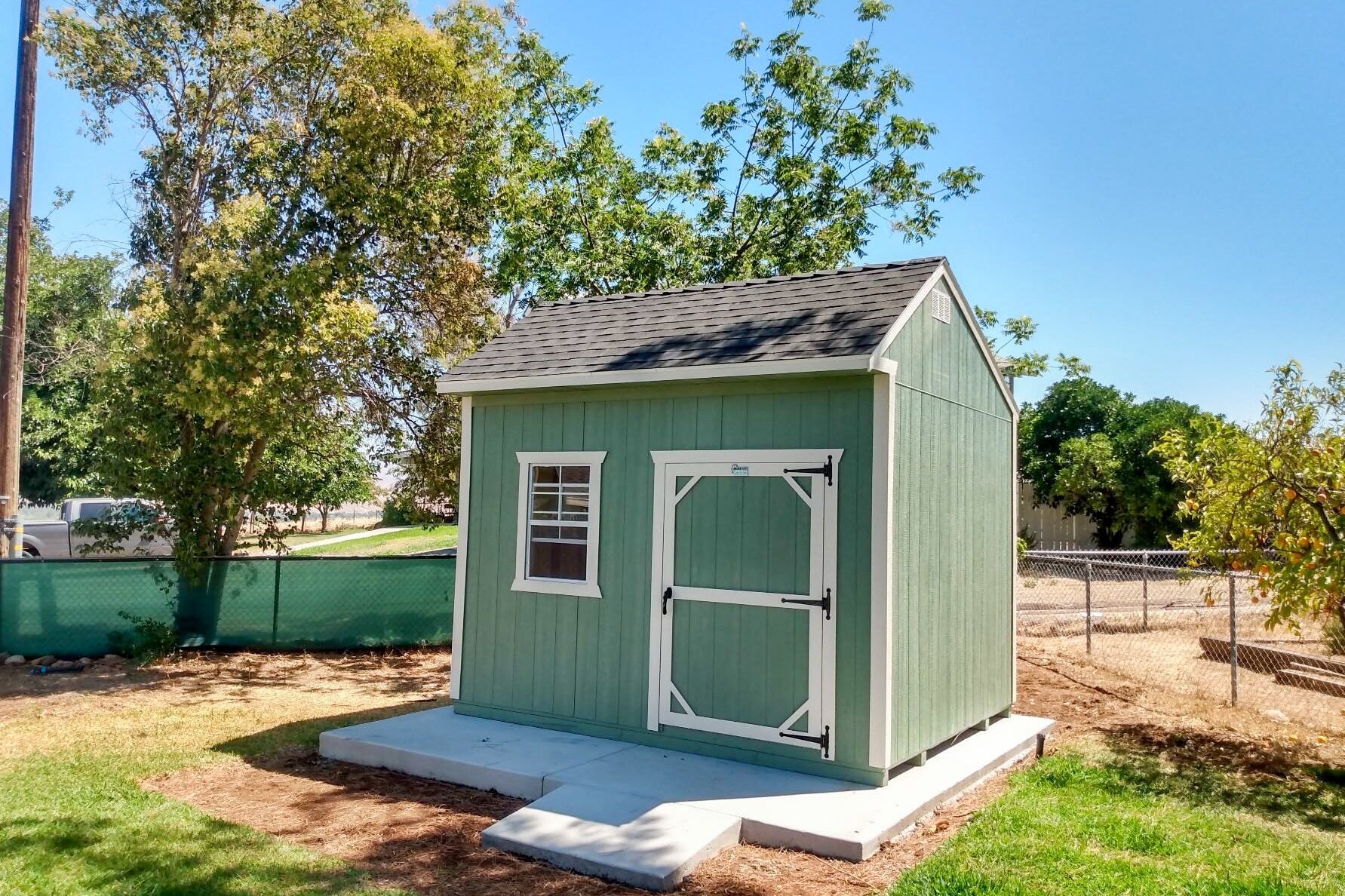 green and white trimmed shed on concrete pad in backyard in California in accordance with shed permit requirements