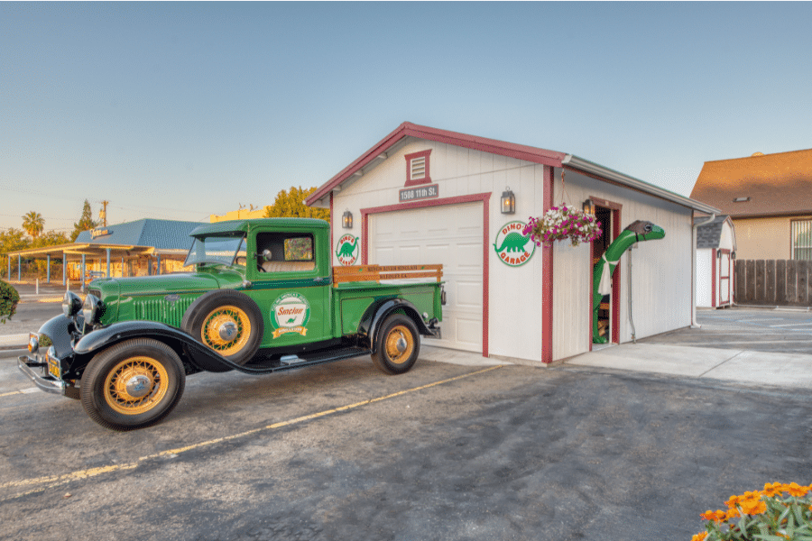 green restored ford sitting in front of Dino's garage 14x20 garage in Reedley, CA with red metal roof and trim and white siding and Sinclair dino poking head out side door