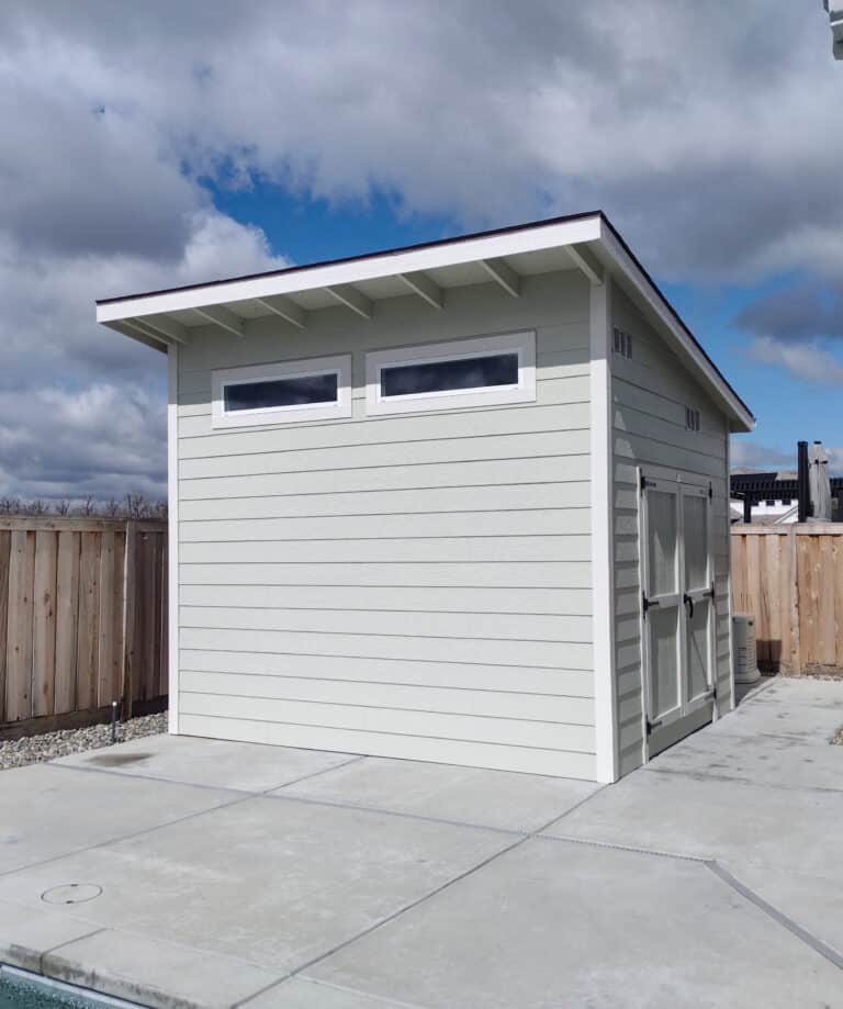 light gray custom lean two storage buildings for sale near Oakhurst CA with two small rectangular windows on front and doors with white trim on side