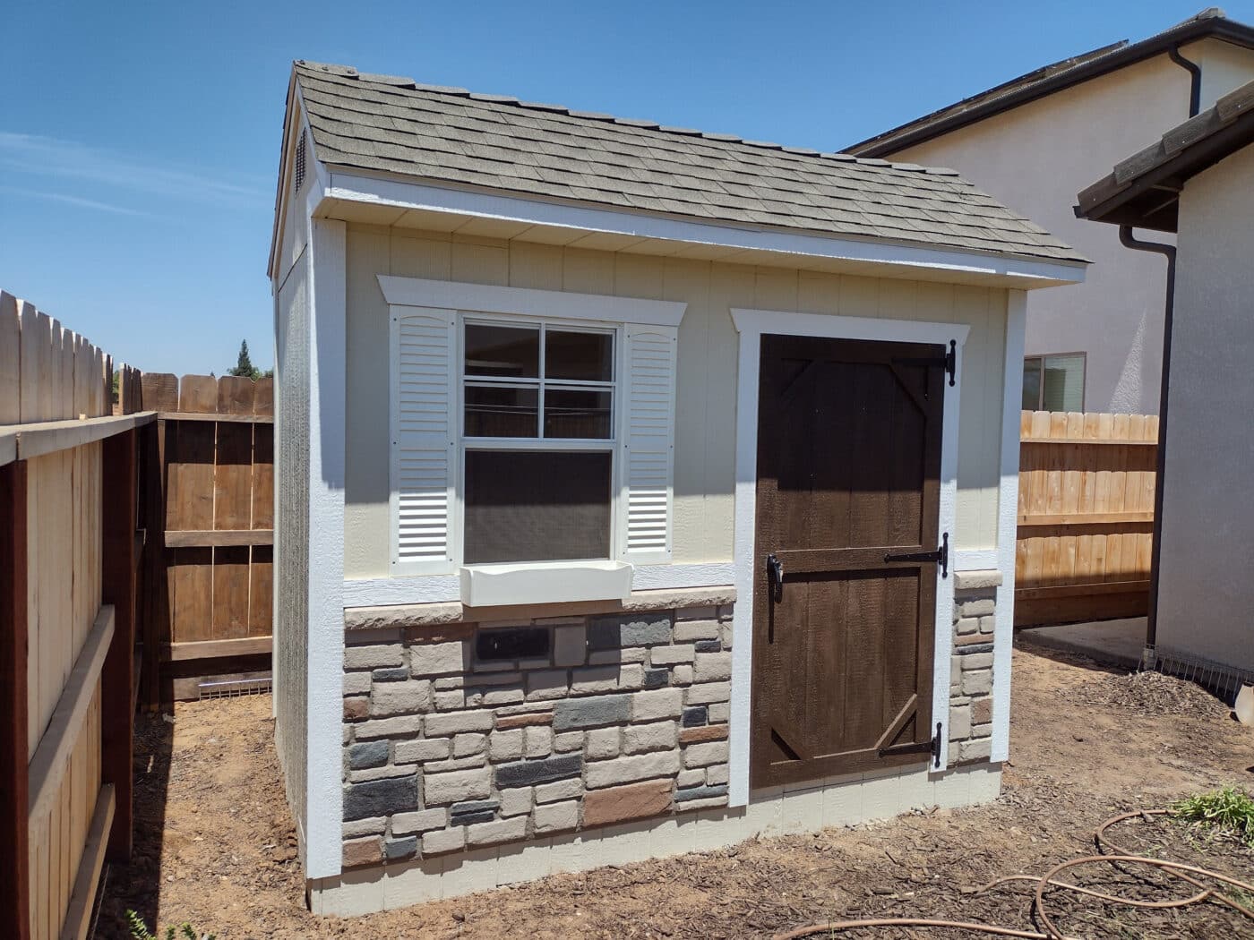 off white deluxe garden shed with white trim brown door and stone detailing at the bottom