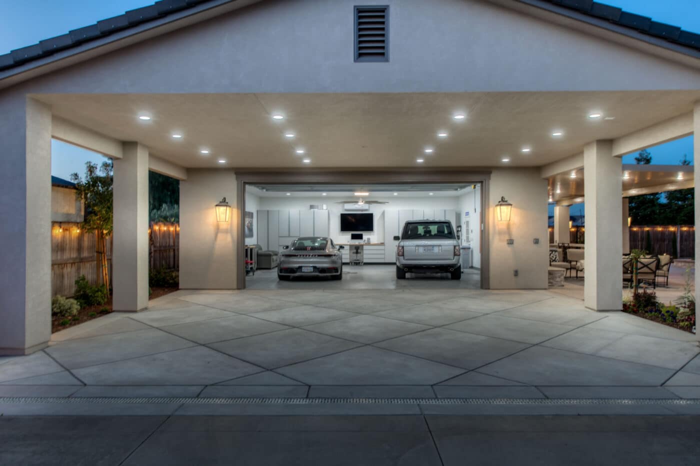 overhang on two car garage with open door showing two cars and lights lit up under overhang at night