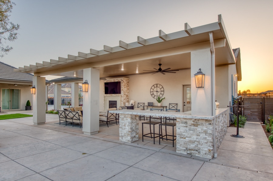 patio attached to 30x50 garage with pergola inspired roof, outdoor kitchen, TV, fireplace, and lounge area