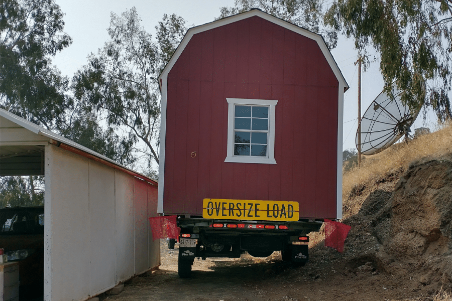 red and white trimmed barn style shed being delivered on site in Squaw Valley, CA