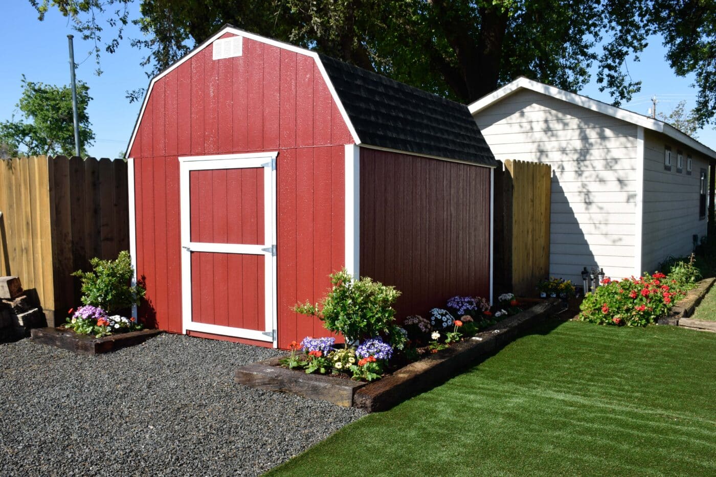 red and white trimmed barn style shed with garden bed around it