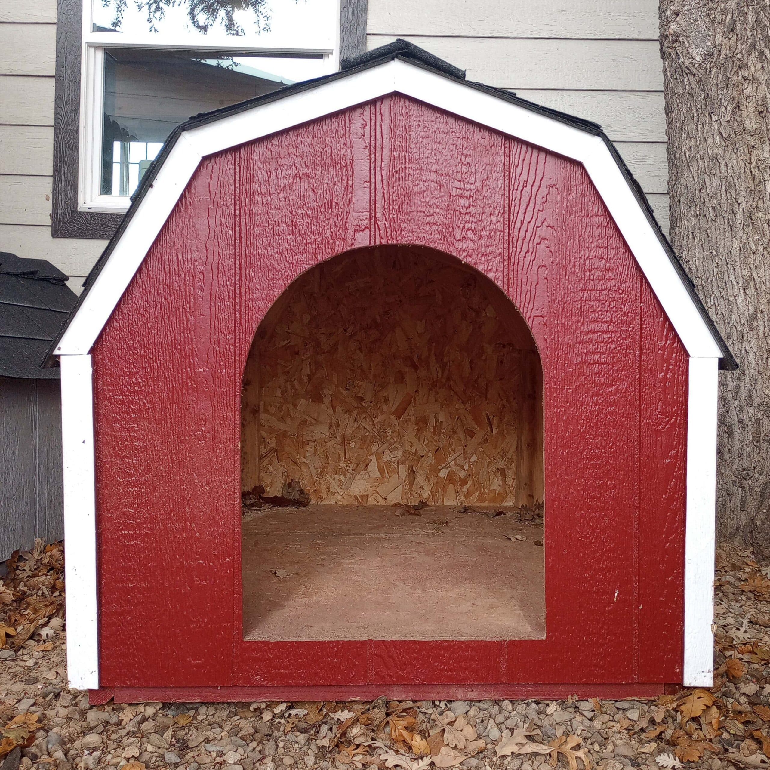 red dog house with black barn style shingle roof and white trim