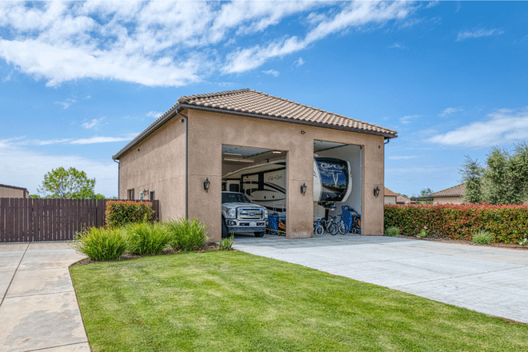 side angle of 32x50 garage with spanish tile roof and two open garage doors revealing RV and truck