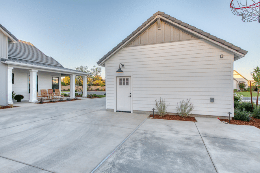 side door on 20x24 2-car garage by basketball hoop and home with black metal roofing and white siding that it matches