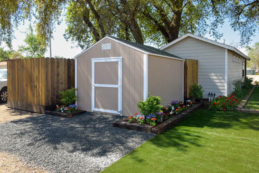 tan and white trimmed ranch shed with flower bed around it