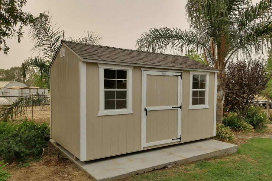tan and white trimmed rancher value shed on concrete pad