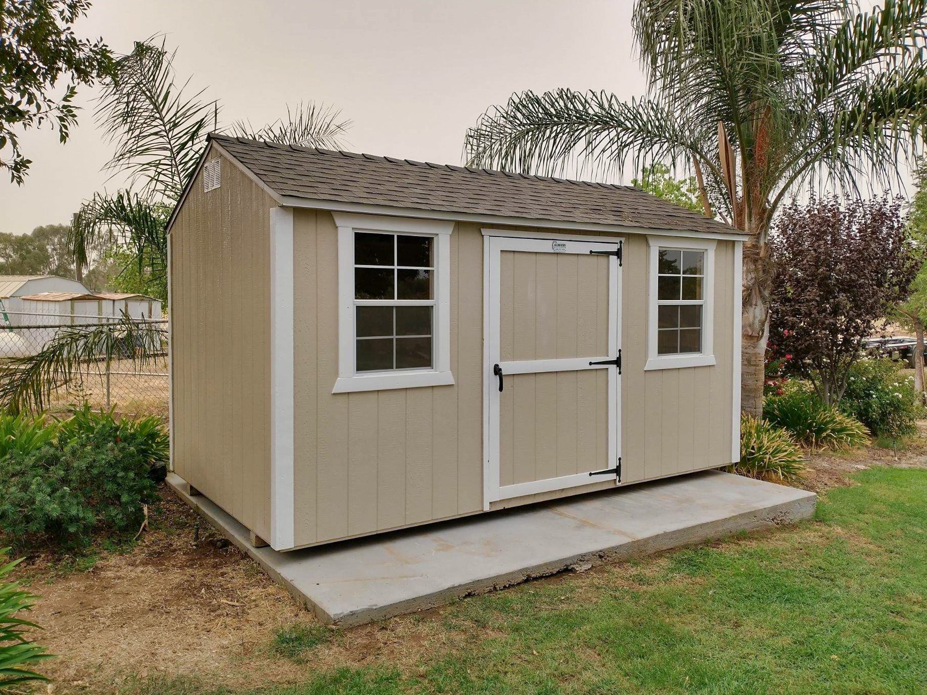 tan rancher shed on concrete pad with white trim