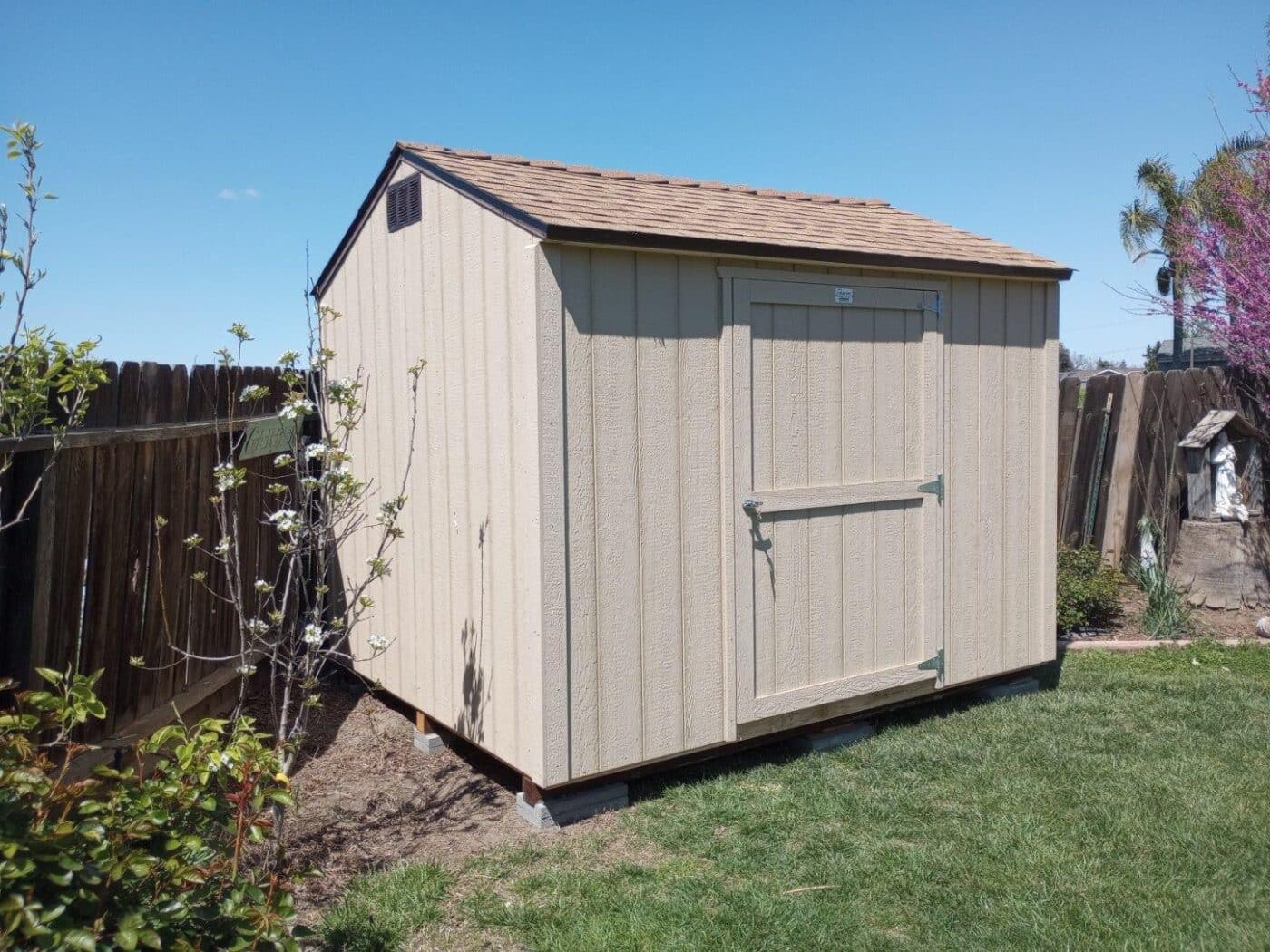 tan rancher value shed in garden by fence