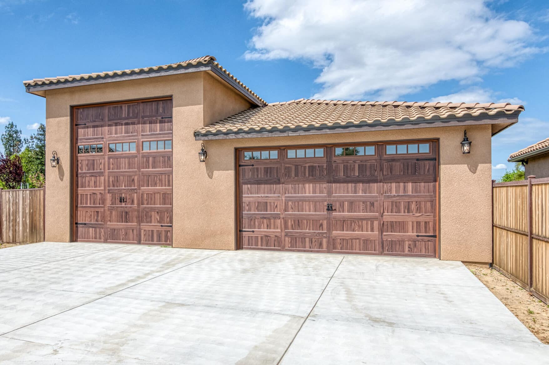 tan stucco sided three car garage with two brown overhead doors