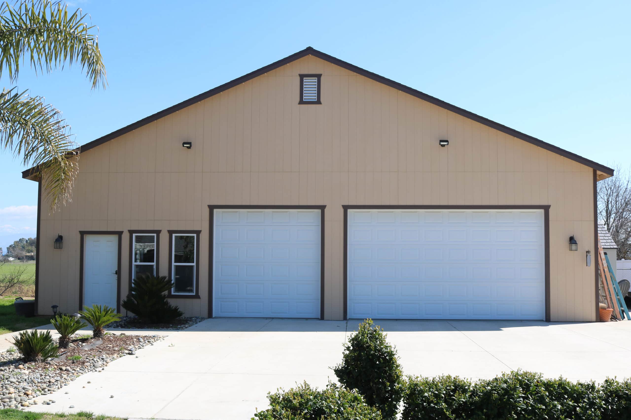 tan three car garages near Tulare CA with brown trim and two white overhead doors