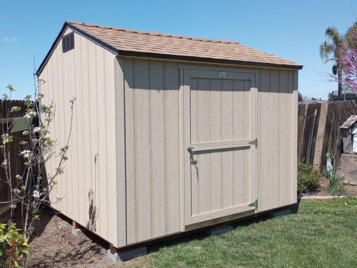 tan wooden rancher value shed with orangish shingle roof