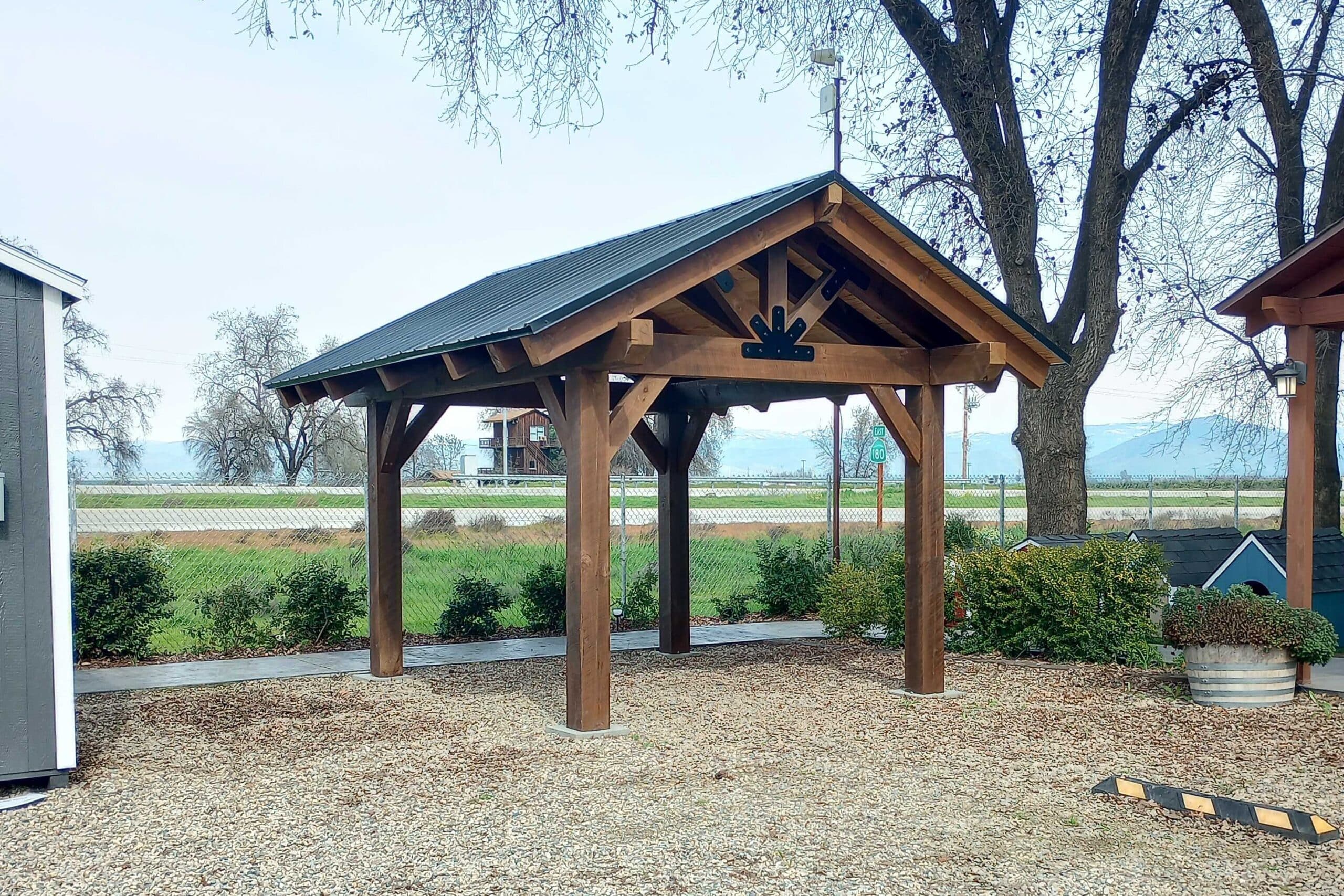 timber frame pavilion with black metal roof in mulch