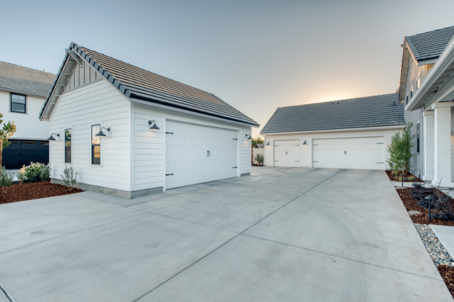 white and black metal roofed 20x24 2-car garage with one white overhead door matching the existing attached garage