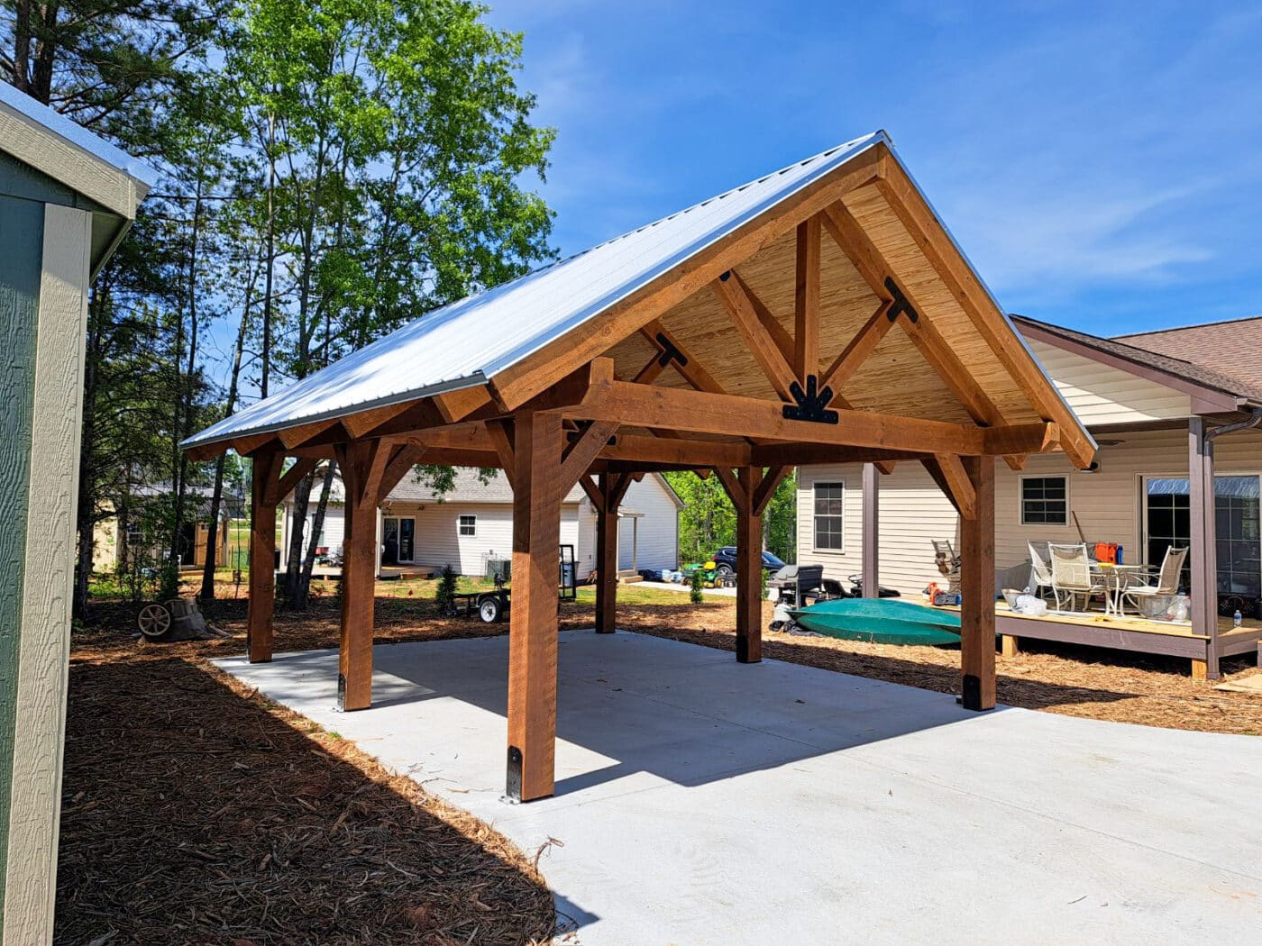 wooden timber frame pavilion on concrete pad between shed and house