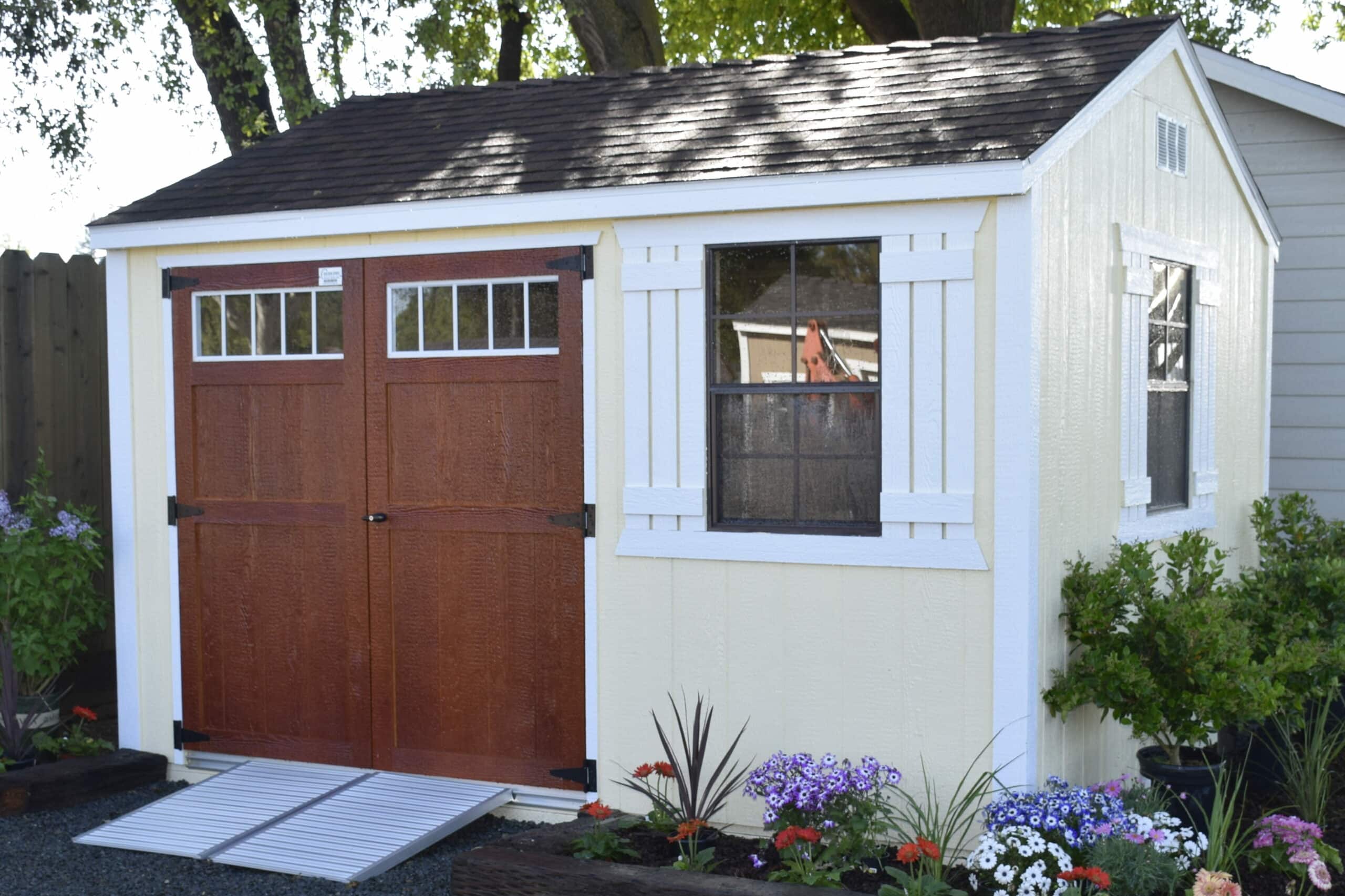 yellow shed with brown doors and white trim surrounded by a garden in Fresno CA