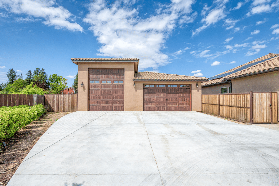 zoomed out view of 32x40 garage with spanish tile roof and stucco siding designed complimentarily to home in CA it's next to